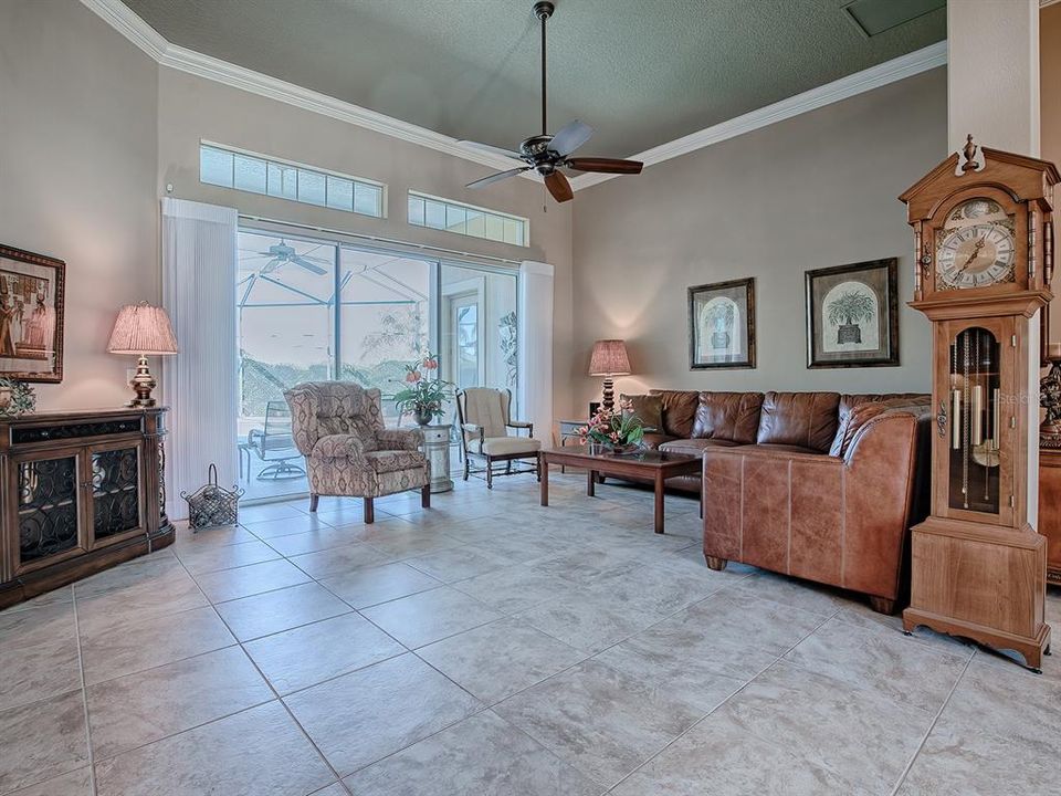 FORMAL LIVING ROOM WITH TRANSOMS OVER SLIDING GLASS DOORS THAT LEAD TO THE POOL AND ARE ENHANCED WITH SILHOUETTE DRAPES.