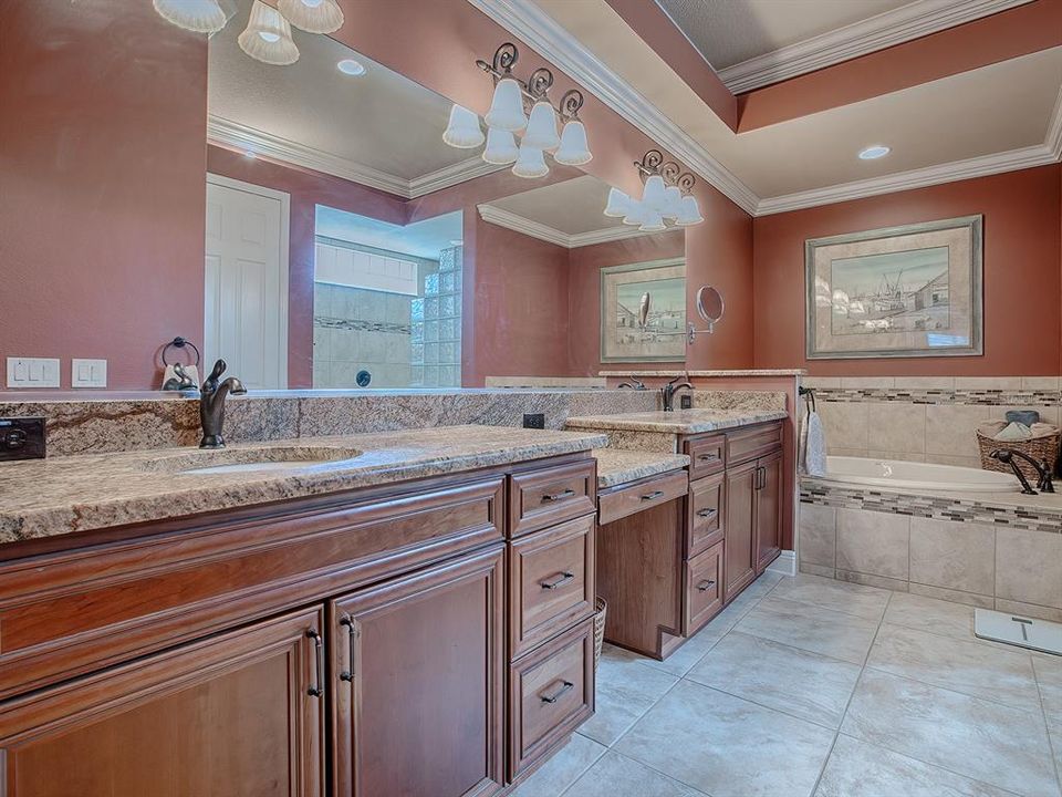 PRIMARY BATH WITH GRANITE COUNTERTOPS, DUAL SINKS, A VANITY, AND A SOAKING TUB.