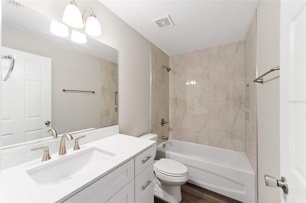 Hall/guest bathroom with ceramic tiled walls and same Quart counters and soft close cabinets