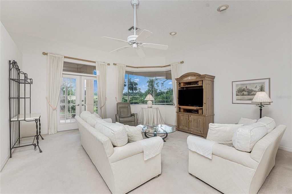 The living room with an aquarium glass window overlooking the large lanai and the golf course in the background.