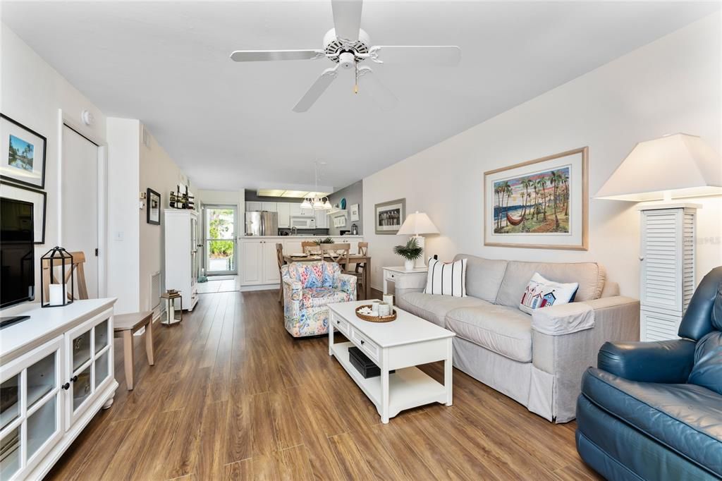 Living area features updated wood flooring and a ceiling fan.