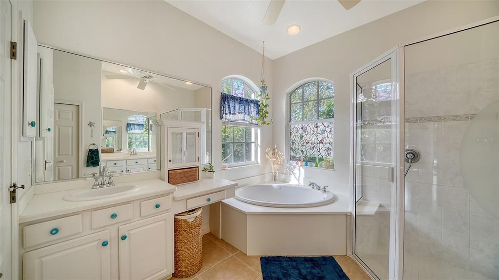 The en-suite bathroom includes a split vanity layout with dual sinks positioned on opposite sides. One sink is of standard-height counter, while the other features a lower counter vanity, ideal for a seated grooming area.