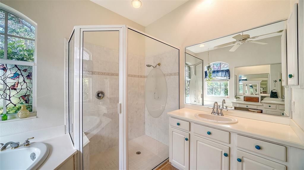 This en-suite bathroom includes a split vanity layout with dual sinks positioned on opposite sides. One sink is of standard-height counter, while the other features a lower counter vanity, ideal for a seated grooming area.