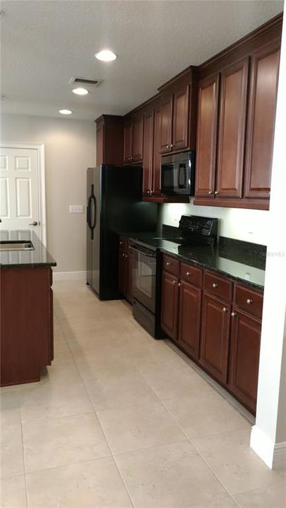 Kitchen with granite counters and mahogany cabinetry.  In addition, there is a walk in pantry.  Lots of storage and space to cook your gourmet meals.