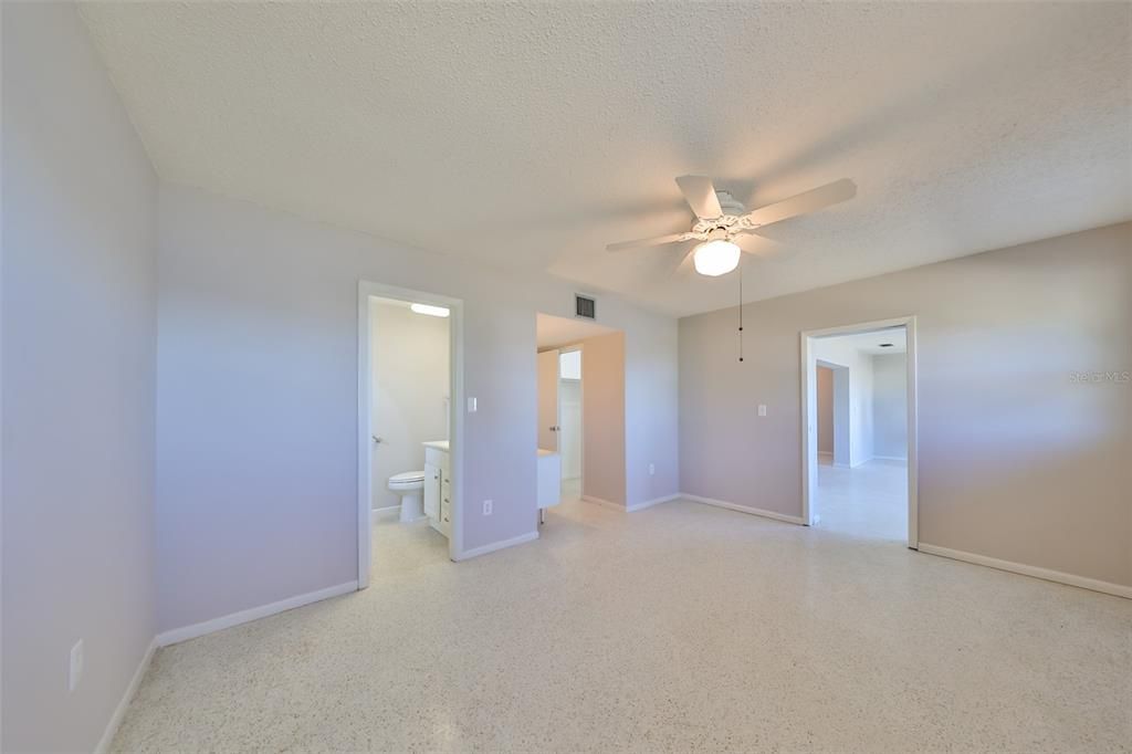 Primary bedroom, ensuite primary bathroom, pocket door to Florida Room on right, center area makeup/vanity and walk-in closet, exit to hall.