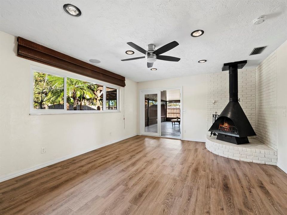 The living room in the back of the home overlooks the huge backyard oasis and features a wood burning fireplace. It opens through storm rated doors to the screened in patio.