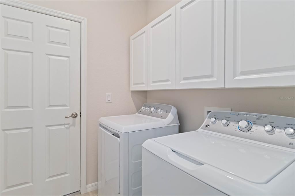 Dedicated laundry room with plenty of cabinets for storage