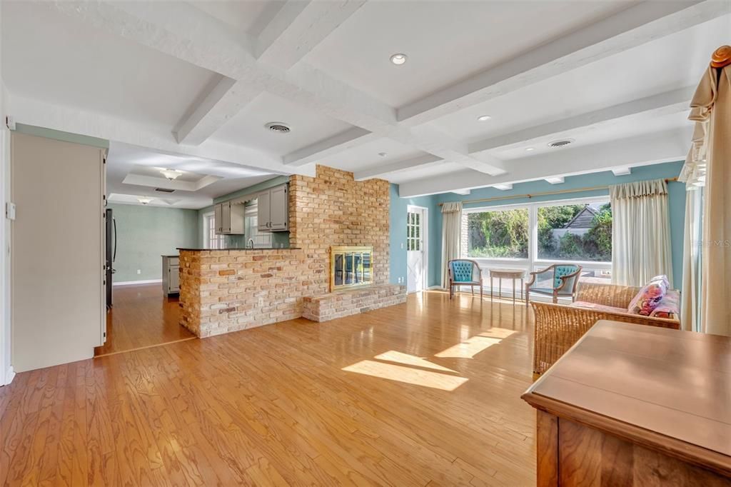 Family Room with brick wood-burning fireplace and a french door leading to the back patio and pool area