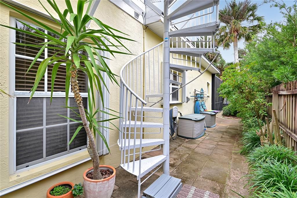 Stairs leading to upstairs entrance and private patio space on the ground level.