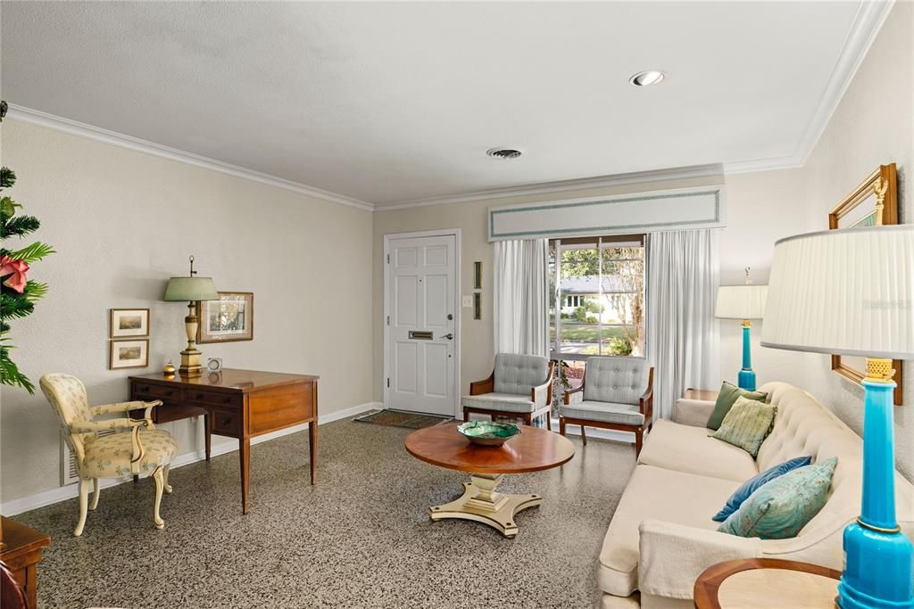 Living room with lots of natural light, crown molding and beautiful terrazzo floors.