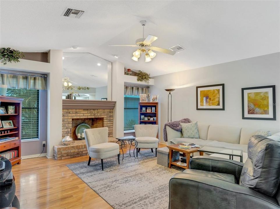 The adjacent family room has a built-in fireplace flanked by large picture windows.