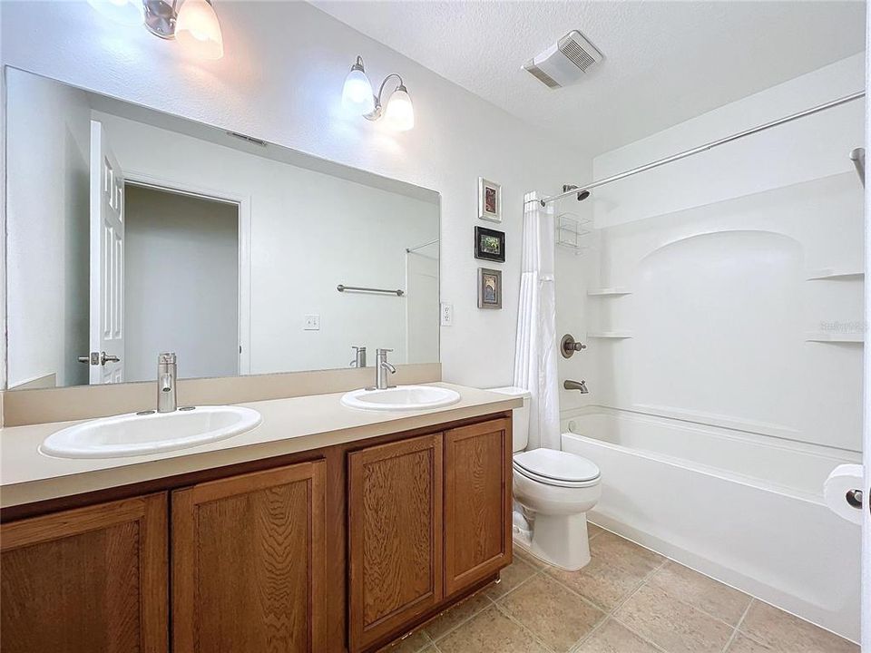 Large hall bath features double vanity and tub with shower and shower shelving