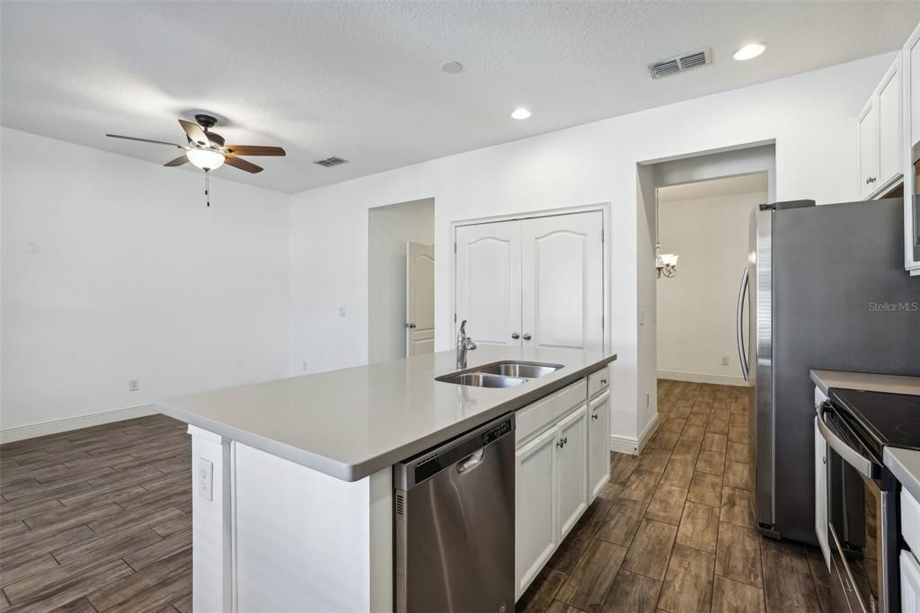 large kitchen that includes an oversized island, Corian Countertops, White Cabinets, Stainless Steel Appliances and Tile Backsplash!