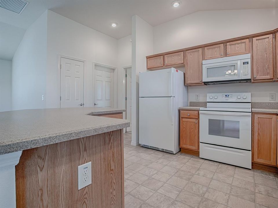 OAK CABINETS WITH NICKEL HARDWARE AND PULL OUTS IN LOWER DRAWERS. THE LEFT DOOR ACROSS FROM THE KITCHEN IS THE CLOSET PANTRY; THE RIGHT IS THE LAUNDRY ROOM.