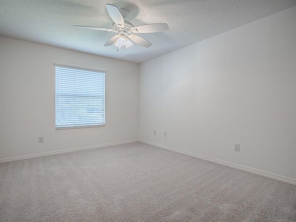 GUEST ROOM WITH CARPET AND CEILING FAN.