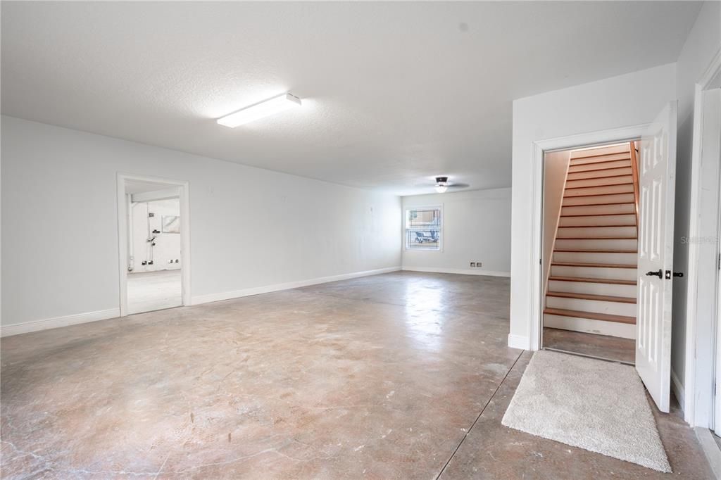 The ground level features a large room with polished cement flooring, accessible through each of the two garages, with stairs leading up to the main floor of the home.