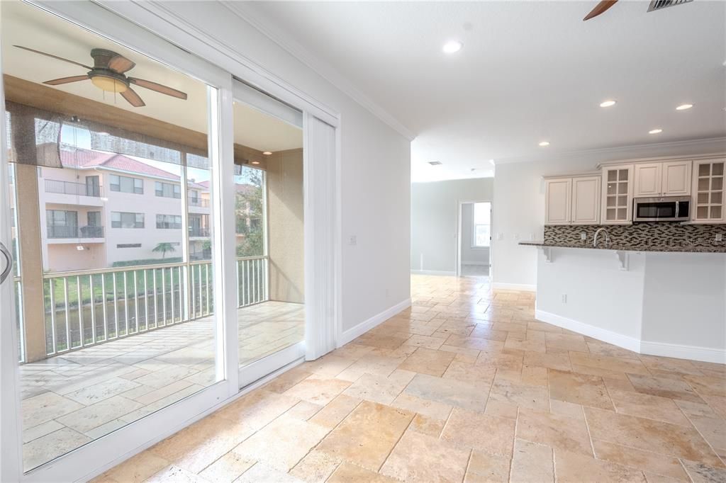 Hurricane impact sliding glass doors open to the expansive screened in, covered balcony with tile floor and ceiling fan.