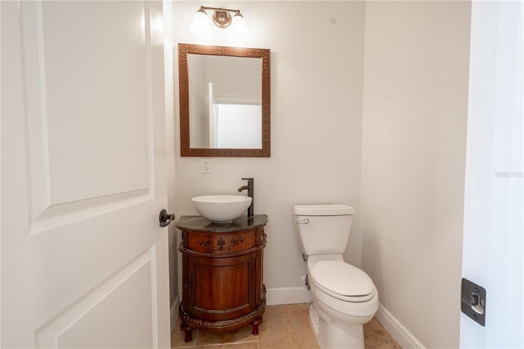 The 2nd bath is a powder room with mirrored vanity with storage, vessel sink and downlight fixture.