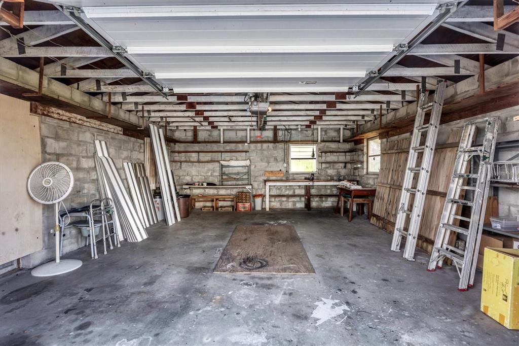 Block garage with power garage door opener, work bench, electricity and side door on the left side.