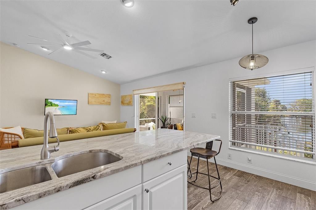 Kitchen with vaulted ceiling, sink, decorative light fixtures, hardwood / wood-style flooring, and white cabinets