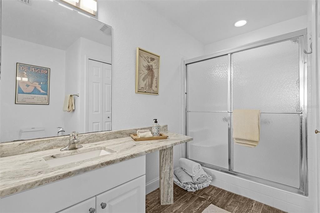 Bathroom featuring hardwood / wood-style floors, vanity, and walk in shower