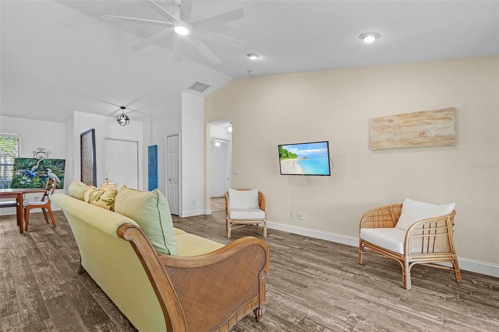 Living room featuring ceiling fan, hardwood / wood-style floors, and lofted ceiling