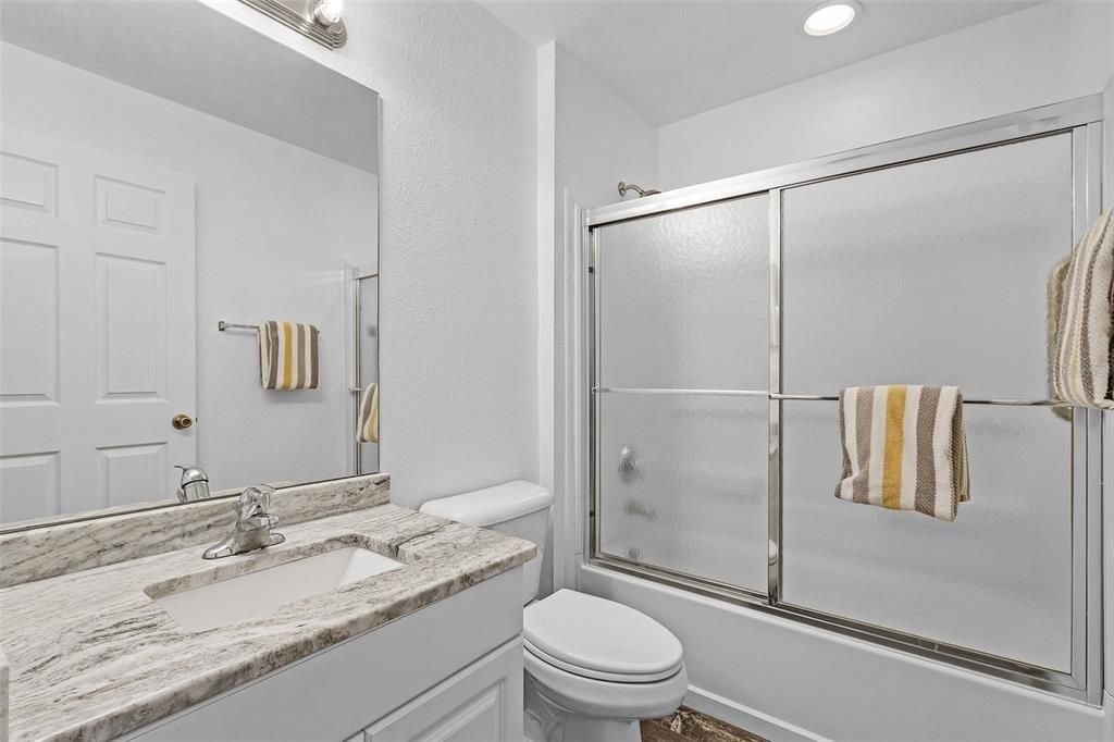 Full bathroom featuring vanity, toilet, and bath / shower combo with glass door