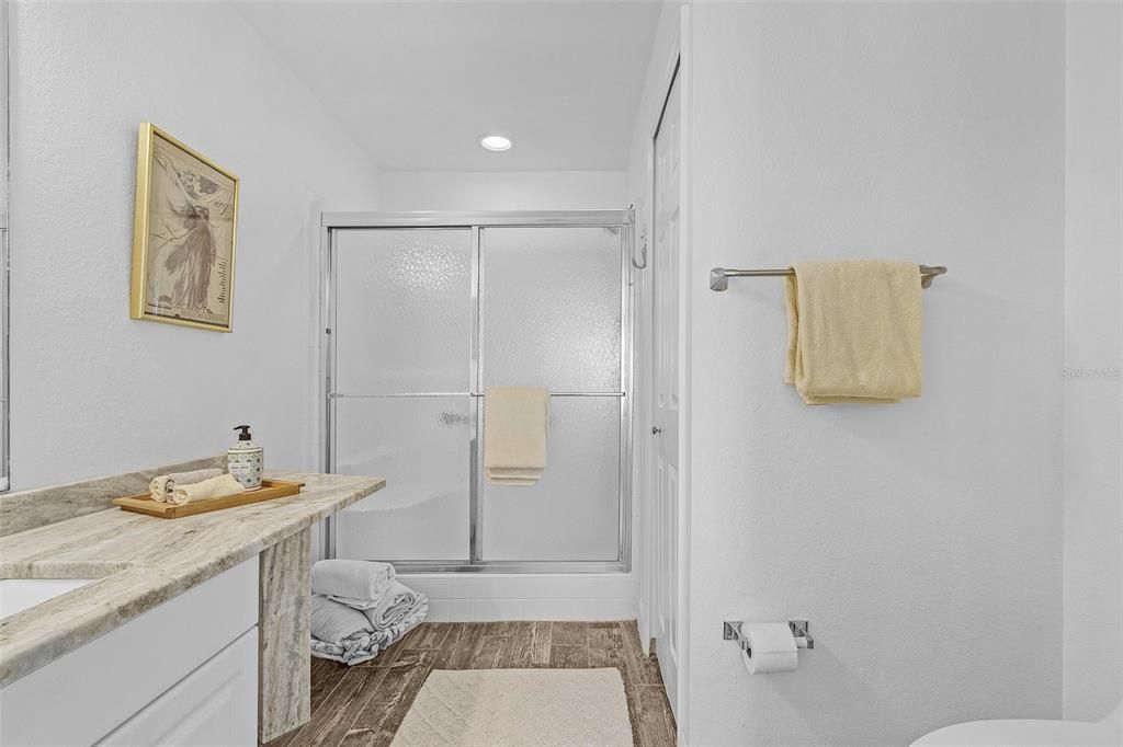 Bathroom with wood-type flooring, vanity, and a shower with door