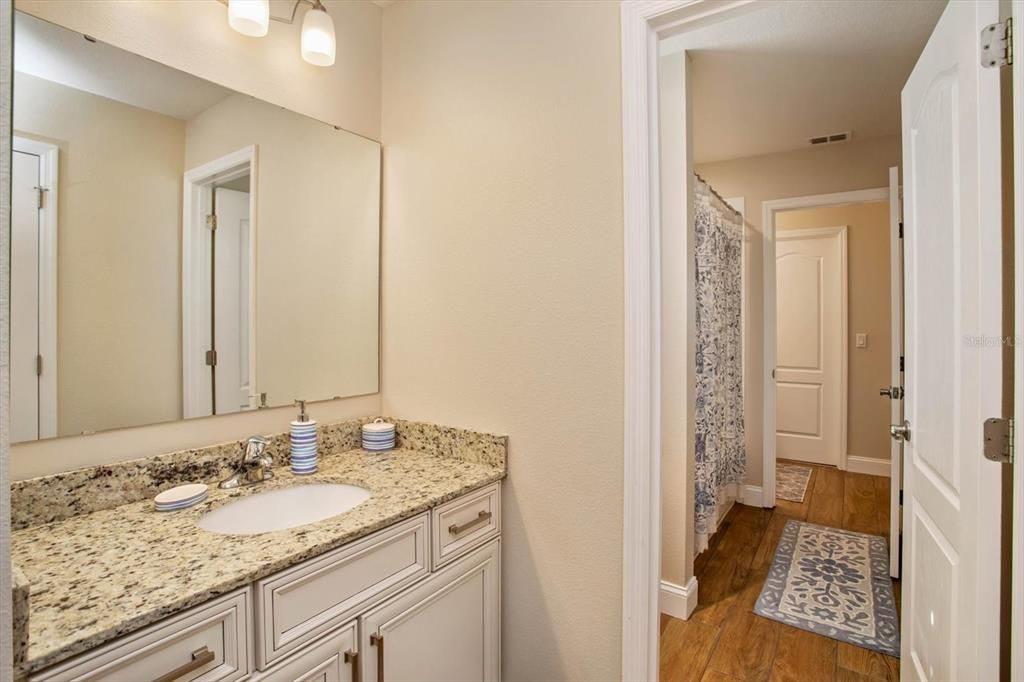 Jack & Jill Bathroom from bedroom #5 and #6.  Sink and cabinets with granite tops on either side, tub/shower and toilet in the middle.