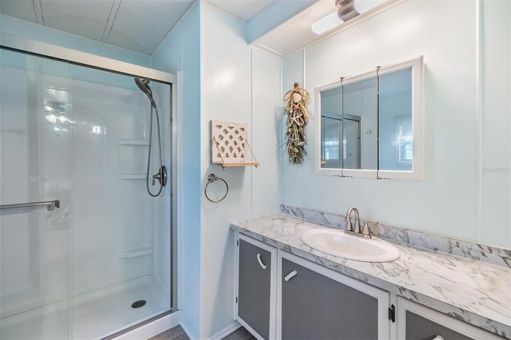 Primary bathroom has updated step-in shower, vanity, sink, fixtures, and flooring.