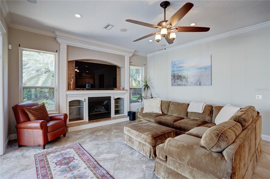 Cozy up by the fireplace while watching TV in the family room overlooking the pool and lanai