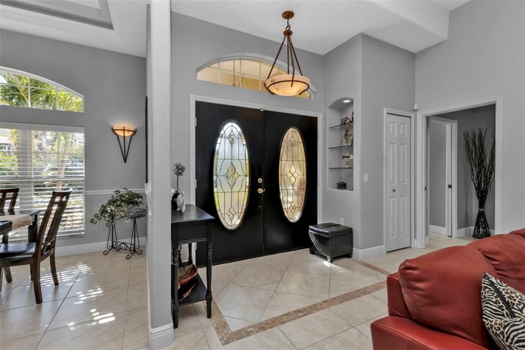 Lovely deco tiled foyer with a cute lighted wall niche, a closet, with primary bedroom on the right and dining area on the left (in this pic).