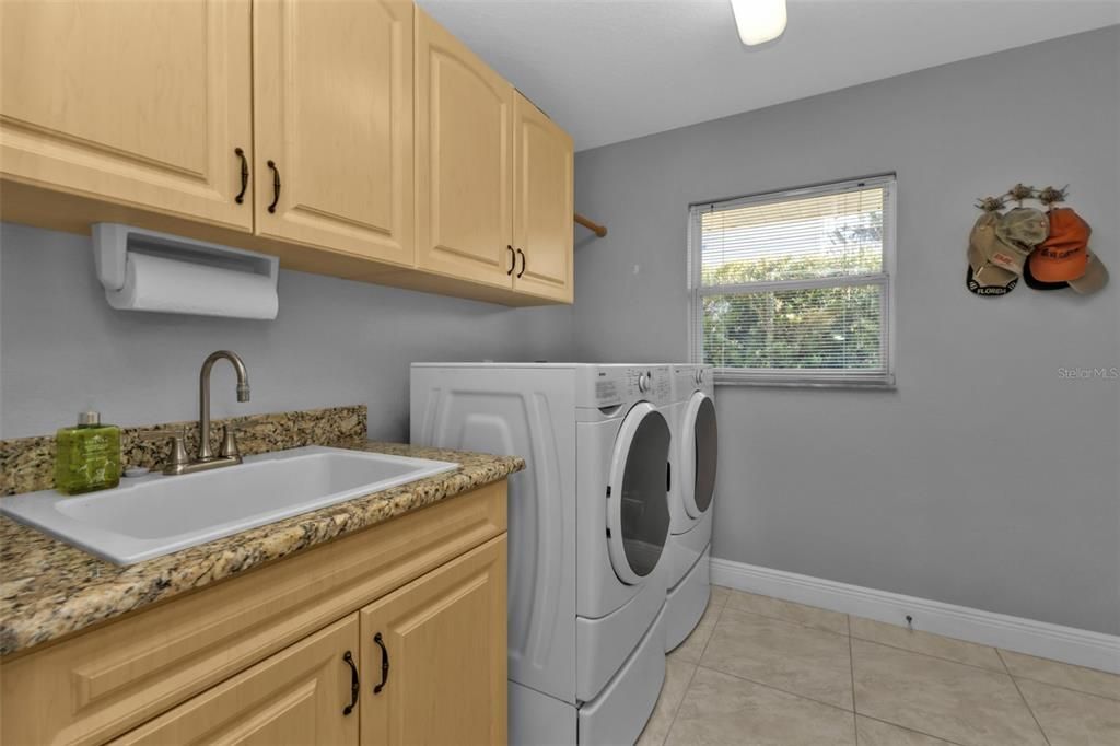 Inside laundry room with built in single vanity sink cabinet and above cabinets. The laundry room leads into the garage. There is also an attic fan to allow more airflow into the attic!