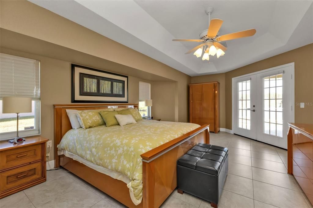 Primary bedroom has a large open space with tray ceilings and french doors out to the lanai and pool/spa area!