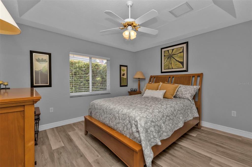 Bedroom 1 with luxury vinyl flooring, tray ceilings, and a large reach in closet.