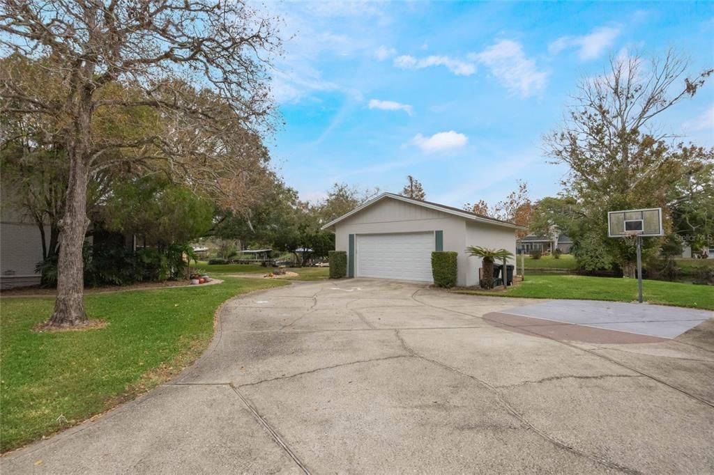 This photo shows the drive way that leads to the detached 2-car garage flanked by mature trees on either side.