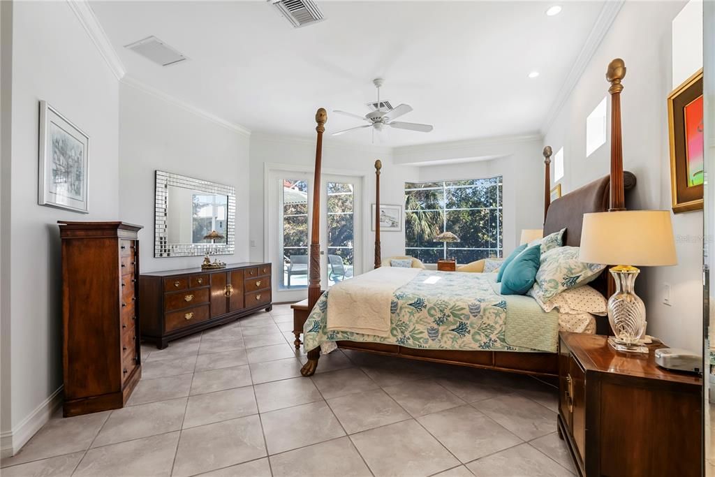 Primary Bedroom with Bay Widow Overlooking Water and Pool and French Doors to Lanai