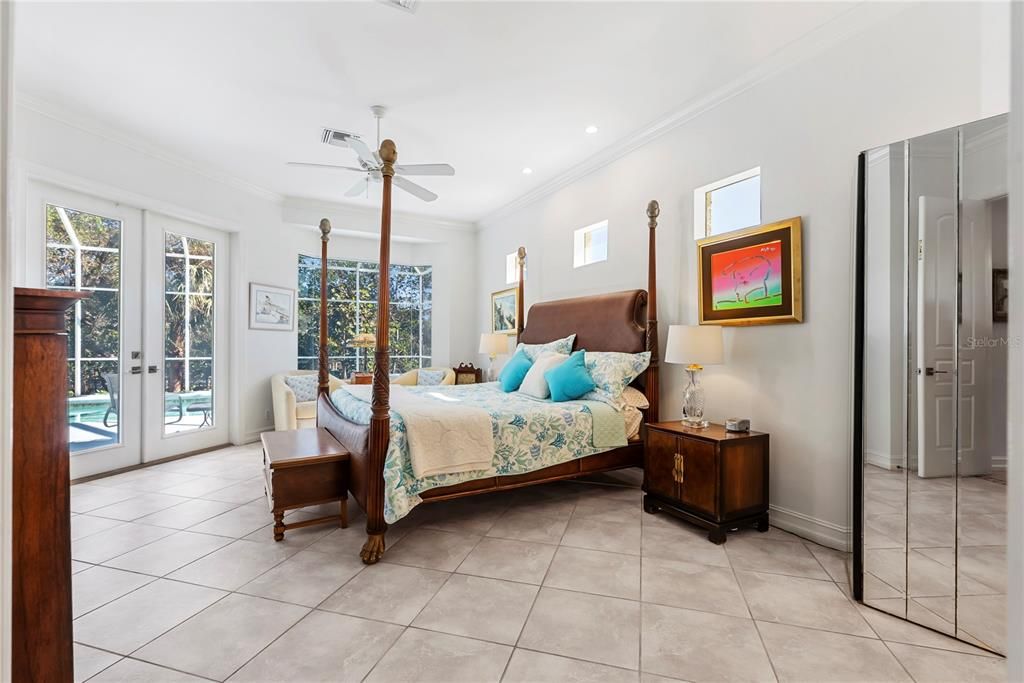 Primary Bedroom with Bay Widow Overlooking Water and Pool and French Doors to Lanai