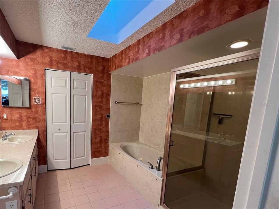 En suite bathroom with jetted tub, shower, skylight