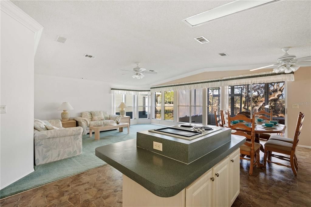 Open concept kitchen, living room, and dining area. Multiple windows look out to golf course.