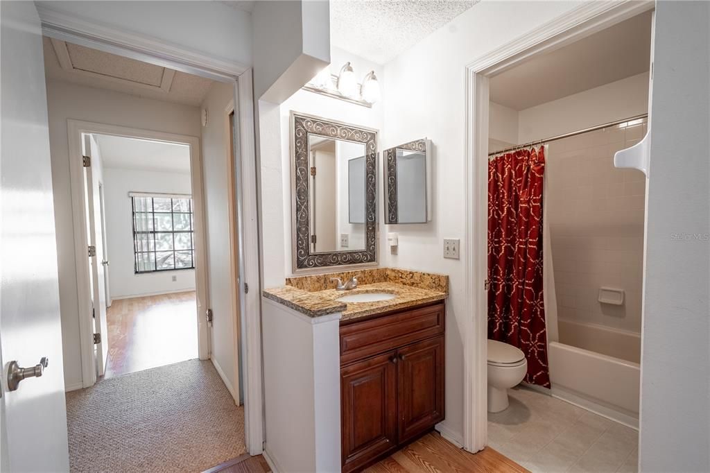 The Primary bathroom (an ensuite) with wood cabinets and granite counters and a tub with shower.