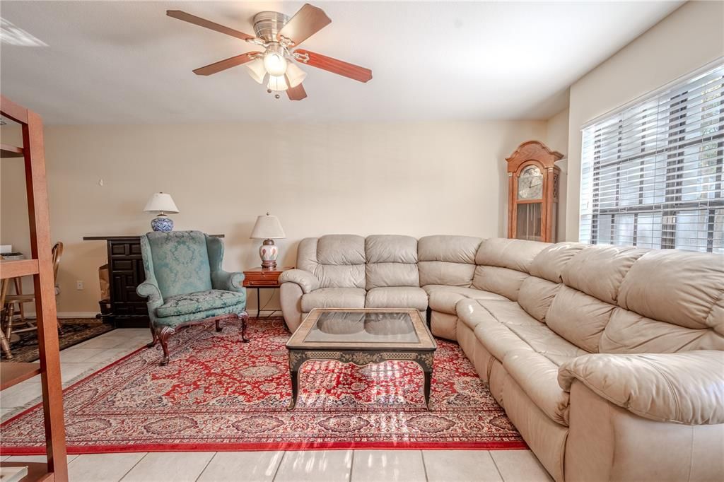 The living room features neutral tones, ceramic tile flooring and a ceiling fan with light kit.