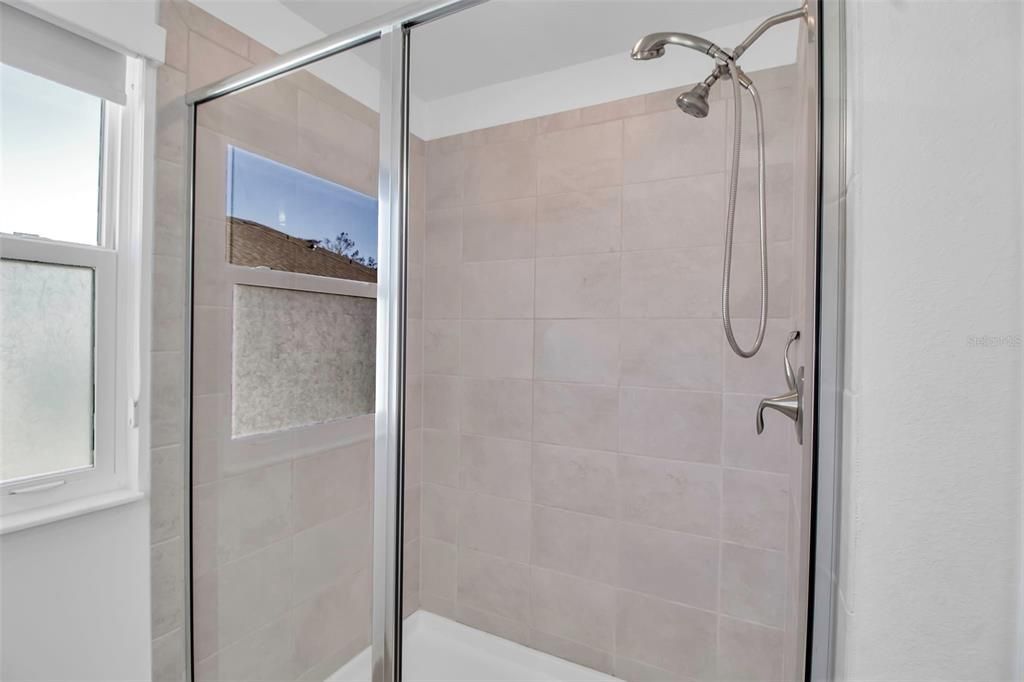 Primary walk in shower with tile surround