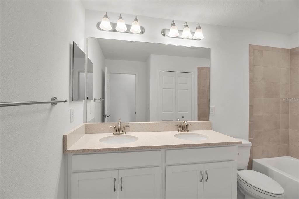 Bath #2 with dual sink vanity and tub/shower with tile surround