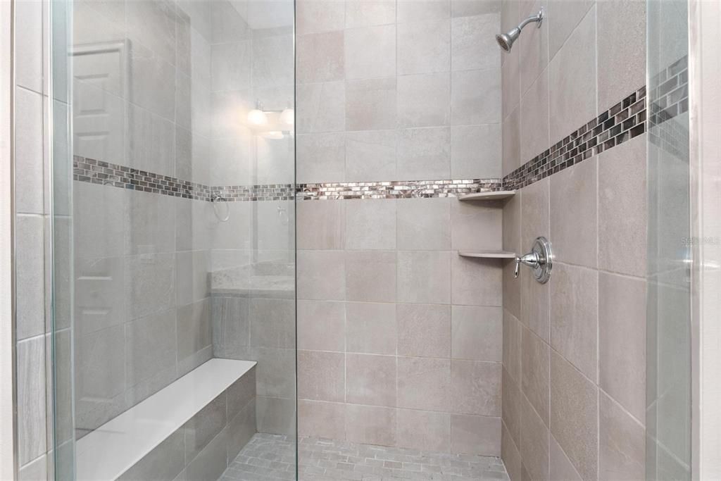 This beautiful custom tiled shower which frame less enclosure and convenient built-in bench.