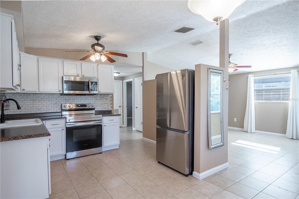 The kitchen features a suite of stainless steel appliances including a French door refrigerator/freezer, a range, and microwave.