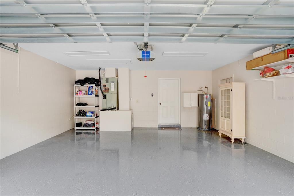 The garage includes epoxy flooring, shelving, a newer opener, and a water softener