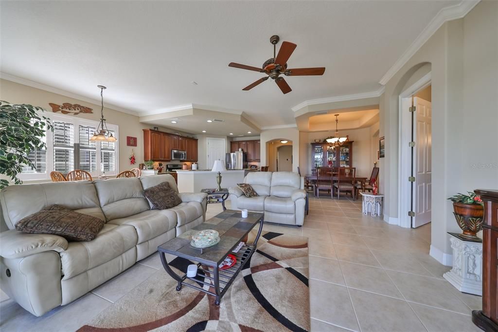 The open floor plan is a welcome amenity in this unit.  Notice the crown molding, architectural features around the door and plantation shutters.