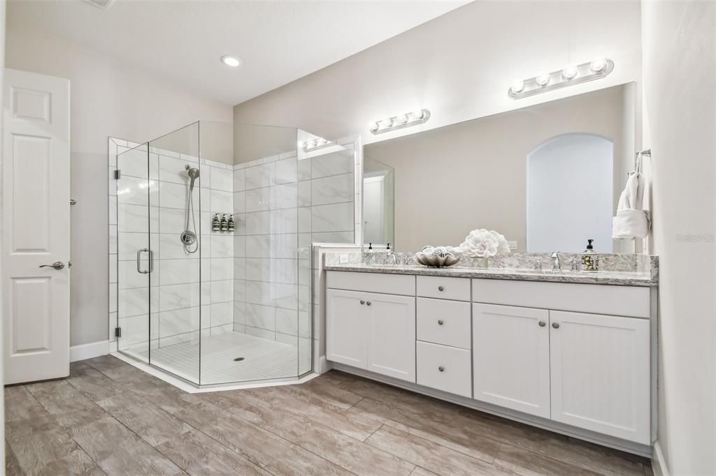 Primary bathroom with double vanity and a private water closet behind a door across from the huge shower.