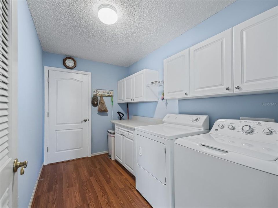 Indoor laundry with extra cabinetry and folding counter.